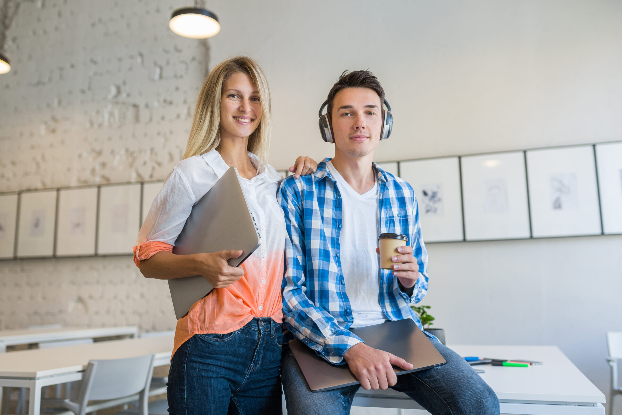young stylish people in co-working office, smiling, happy, startup, freelancers, modern office room, open space, workplace, student learning, man in headphones drinking coffee, woman holding laptop